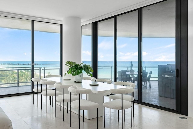 dining area featuring light tile patterned floors, a wall of windows, and a water view