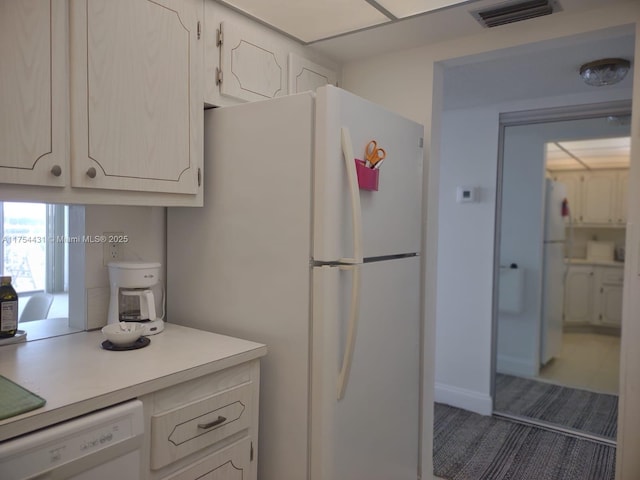 kitchen with visible vents, white appliances, white cabinetry, and light countertops