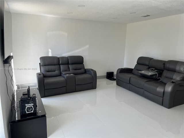 living room featuring tile patterned flooring, visible vents, and a textured ceiling