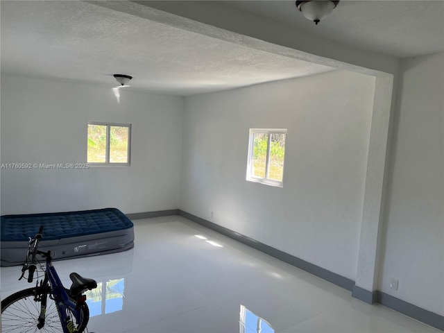 interior space with a wealth of natural light, baseboards, and a textured ceiling