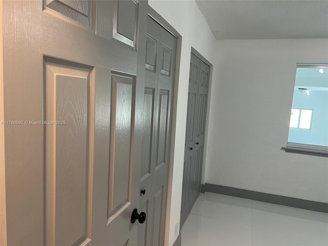 hallway featuring tile patterned floors and baseboards