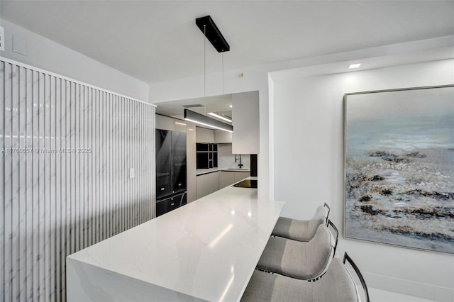 kitchen with a peninsula, a sink, hanging light fixtures, black electric stovetop, and modern cabinets