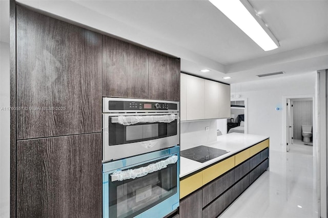 kitchen with visible vents, stainless steel double oven, dark brown cabinets, white cabinetry, and black electric stovetop