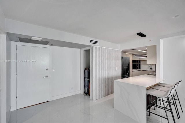 kitchen with visible vents, a breakfast bar, a peninsula, light countertops, and modern cabinets