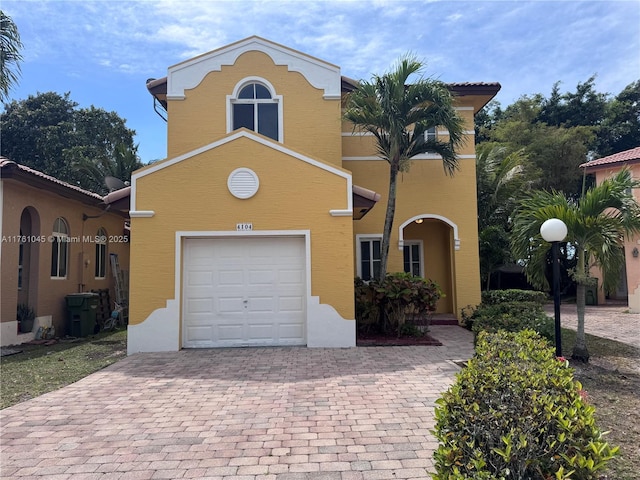 view of front of property featuring stucco siding, decorative driveway, and a garage