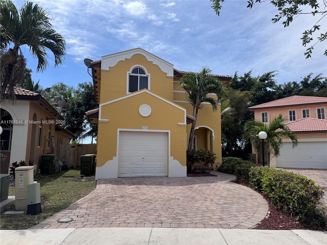 view of front facade with fence, central AC, stucco siding, a garage, and decorative driveway