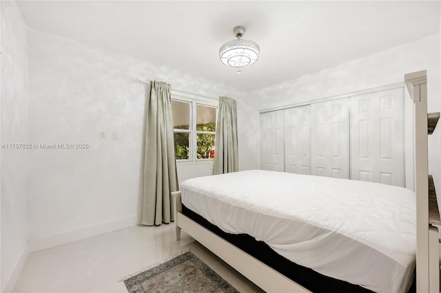 bedroom with tile patterned floors, a closet, and baseboards