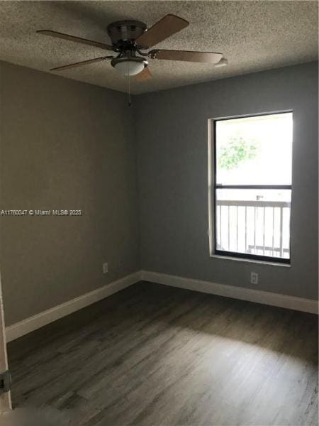 empty room featuring dark wood-style floors, a textured ceiling, baseboards, and a ceiling fan