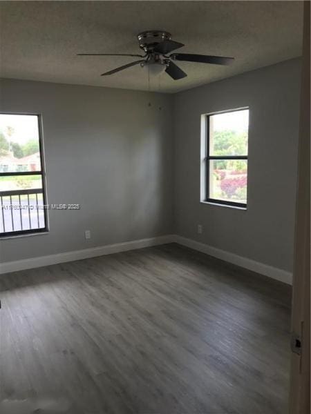 empty room featuring a textured ceiling, a ceiling fan, baseboards, and wood finished floors