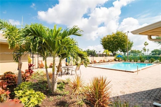 community pool with a patio and fence