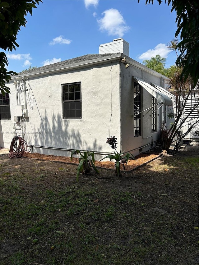 view of home's exterior with crawl space, stucco siding, and roof with shingles