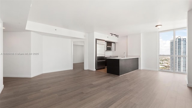 kitchen with wood finished floors, a peninsula, floor to ceiling windows, appliances with stainless steel finishes, and open floor plan