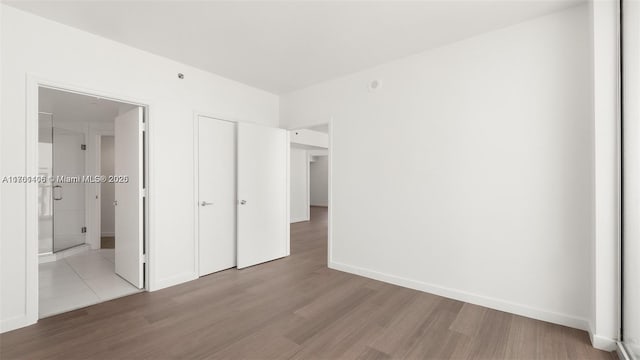 55 SE 6th St Unit 3701, Miami, FL 33131 - unfurnished bedroom with ensuite bath, baseboards, and wood finished floors