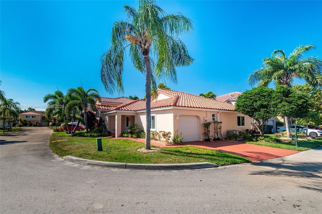 mediterranean / spanish-style house featuring stucco siding, a garage, a front yard, and a tiled roof