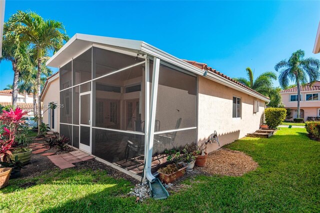 1154 SE 6th Ct, Dania Beach, FL 33004 - view of property exterior featuring stucco siding, a lawn, a tile roof, and a sunroom