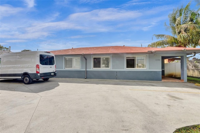 ranch-style home with stucco siding, concrete driveway, and fence