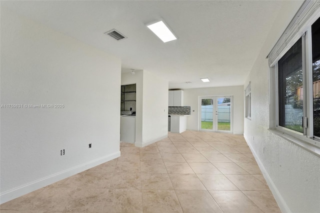 unfurnished room featuring light tile patterned floors, visible vents, and baseboards