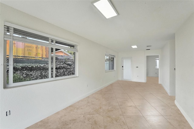 tiled empty room featuring baseboards