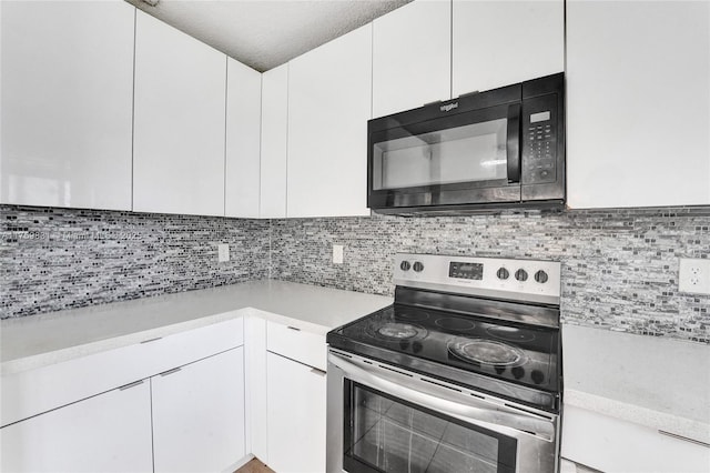 kitchen featuring light countertops, white cabinets, electric stove, and black microwave