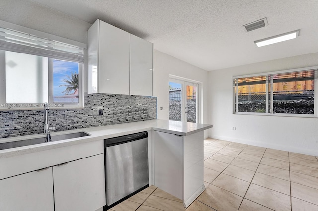 kitchen with visible vents, a sink, backsplash, light countertops, and dishwasher