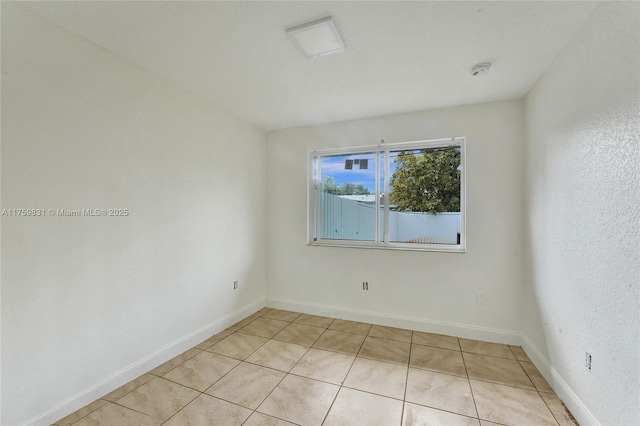 empty room with light tile patterned flooring and baseboards