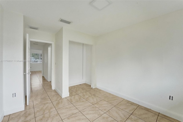 spare room with light tile patterned flooring, visible vents, and baseboards