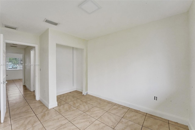 unfurnished bedroom featuring light tile patterned floors, a closet, baseboards, and visible vents