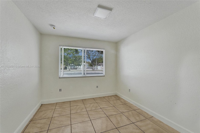 empty room with a textured wall, baseboards, and a textured ceiling