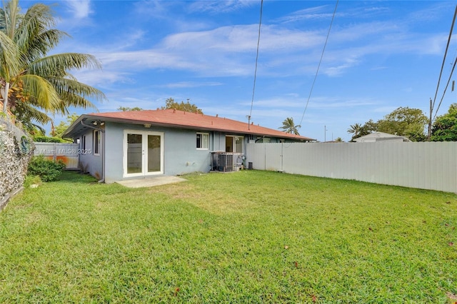 rear view of property featuring a lawn, a fenced backyard, and stucco siding