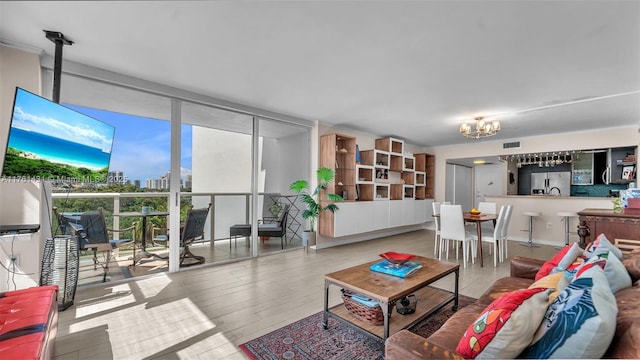 living room with visible vents, an inviting chandelier, and floor to ceiling windows