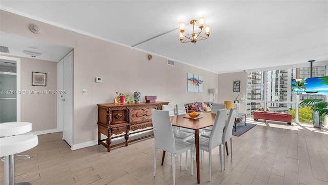 dining room with baseboards, visible vents, light wood finished floors, and ornamental molding