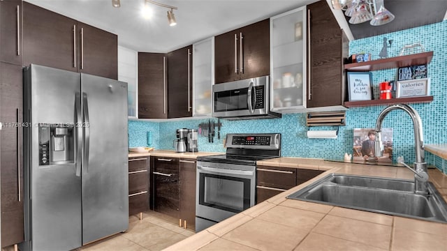 kitchen with light tile patterned flooring, a sink, dark brown cabinetry, appliances with stainless steel finishes, and backsplash