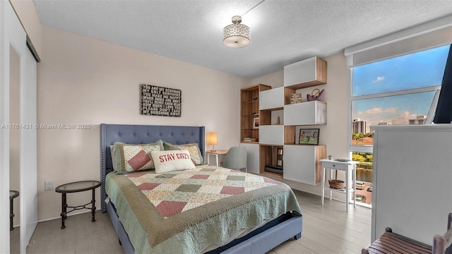 bedroom with light wood-style floors, expansive windows, and a textured ceiling