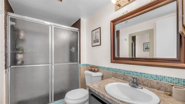 full bath with tile walls, a stall shower, toilet, and vanity