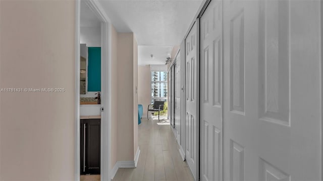 hall featuring light wood-style floors and baseboards