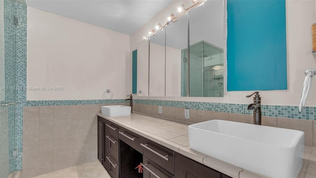 full bath with tile walls, tile patterned floors, a shower stall, and a sink