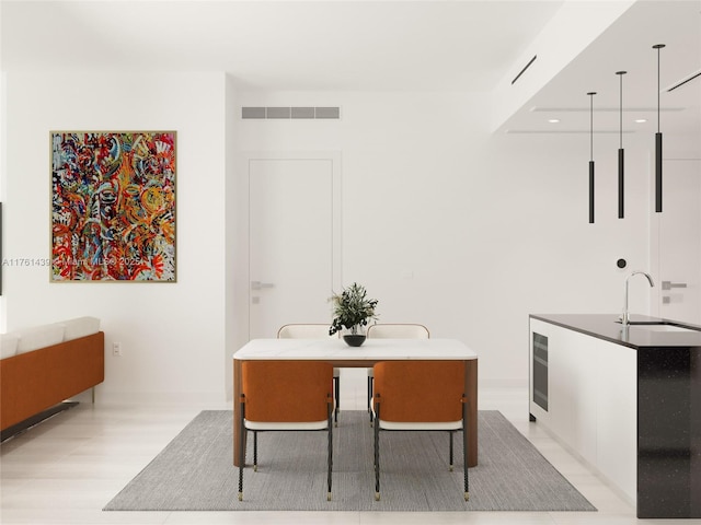 dining area featuring beverage cooler, visible vents, and light wood-type flooring