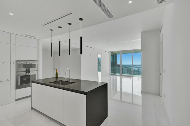 kitchen featuring a wall of windows, visible vents, a sink, dark countertops, and modern cabinets