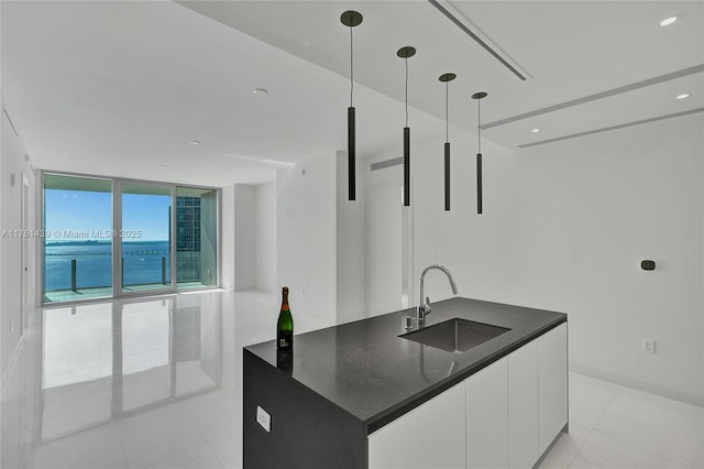 kitchen with modern cabinets, a sink, decorative light fixtures, floor to ceiling windows, and white cabinetry