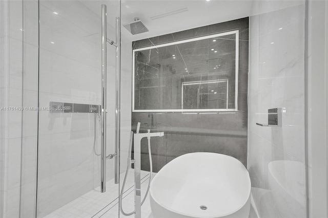 bathroom with a shower stall and tile walls