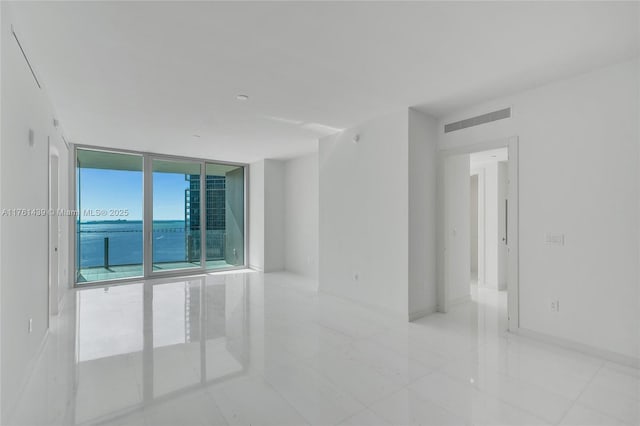 empty room with visible vents, floor to ceiling windows, and baseboards