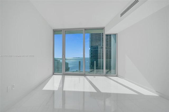 unfurnished room with a wall of windows, visible vents, and baseboards