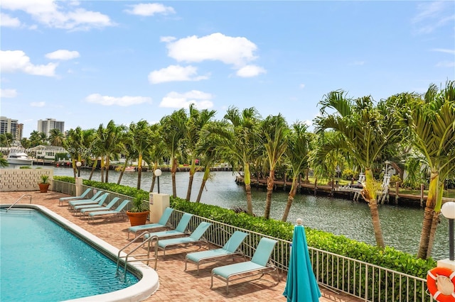 pool with fence, a patio area, and a water view