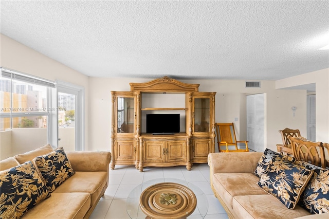 living room featuring light tile patterned floors, visible vents, and a textured ceiling