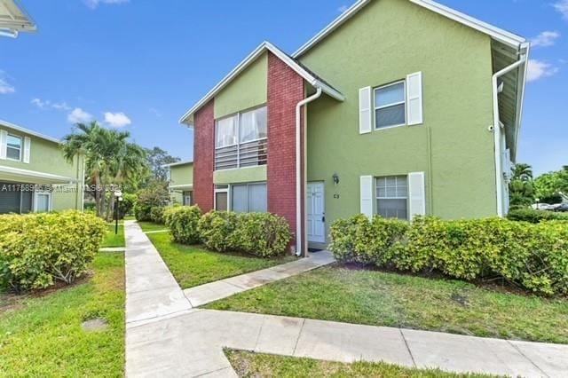 view of property featuring a front lawn and stucco siding