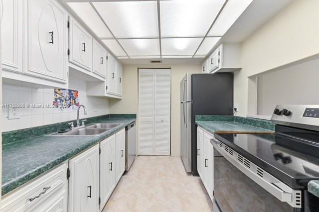 kitchen featuring dark countertops, white cabinets, stainless steel appliances, and a sink