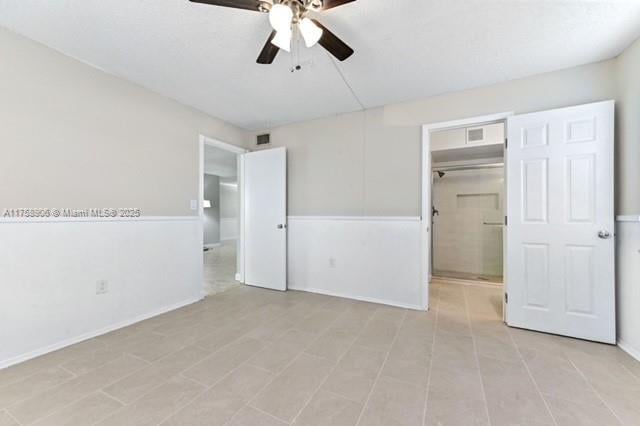 unfurnished bedroom with a walk in closet, a ceiling fan, visible vents, and a closet