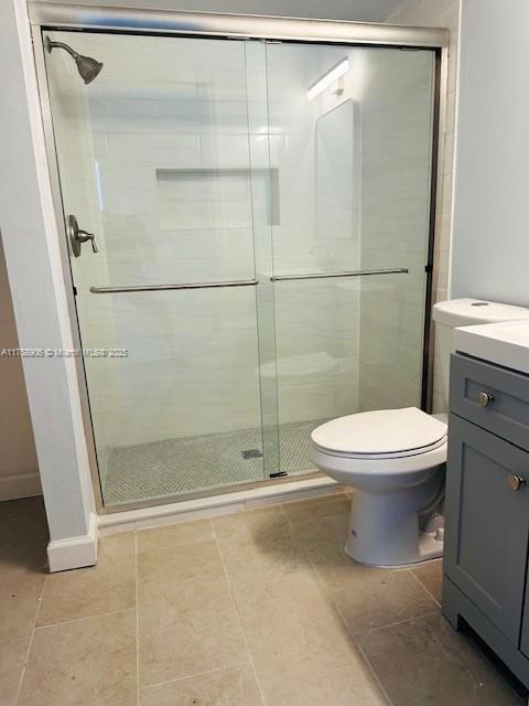 bathroom featuring toilet, a shower stall, and vanity