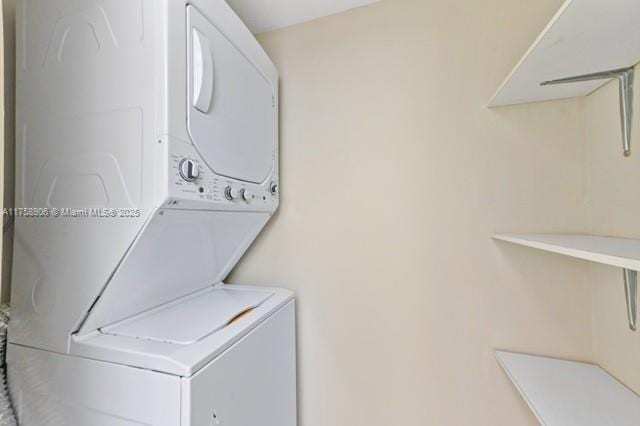 clothes washing area featuring stacked washer / dryer and laundry area