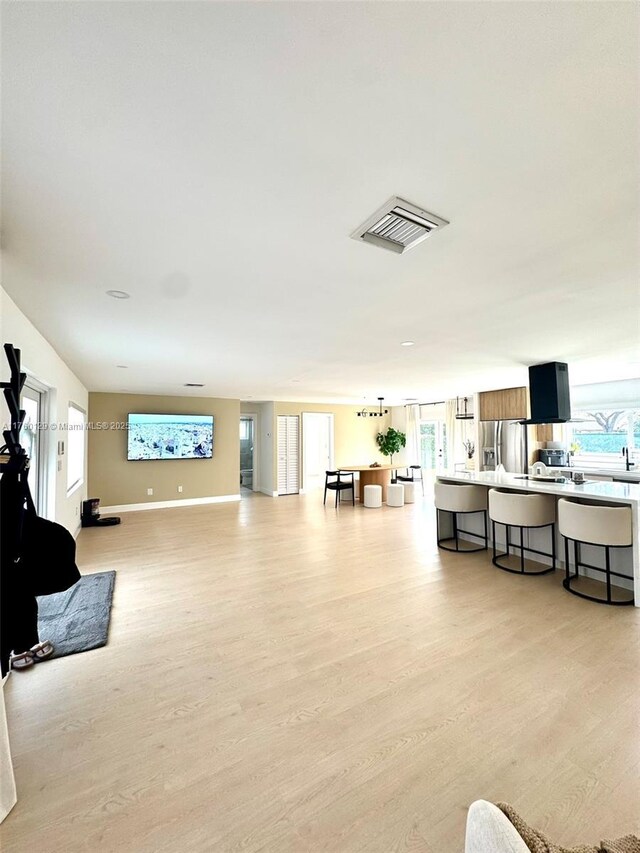 living room featuring light wood finished floors, visible vents, and a wealth of natural light